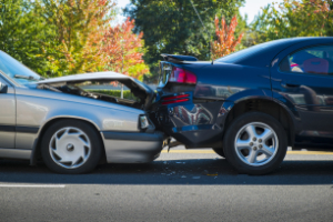 Two cars involved in a rear-end collision with visible damage to the trunk and hood.